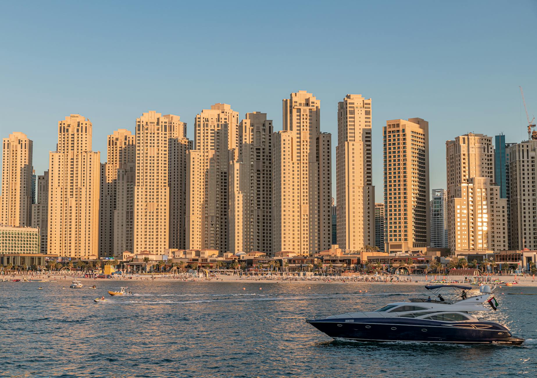 a yacht sailing on the sea near the city buildings by the beach